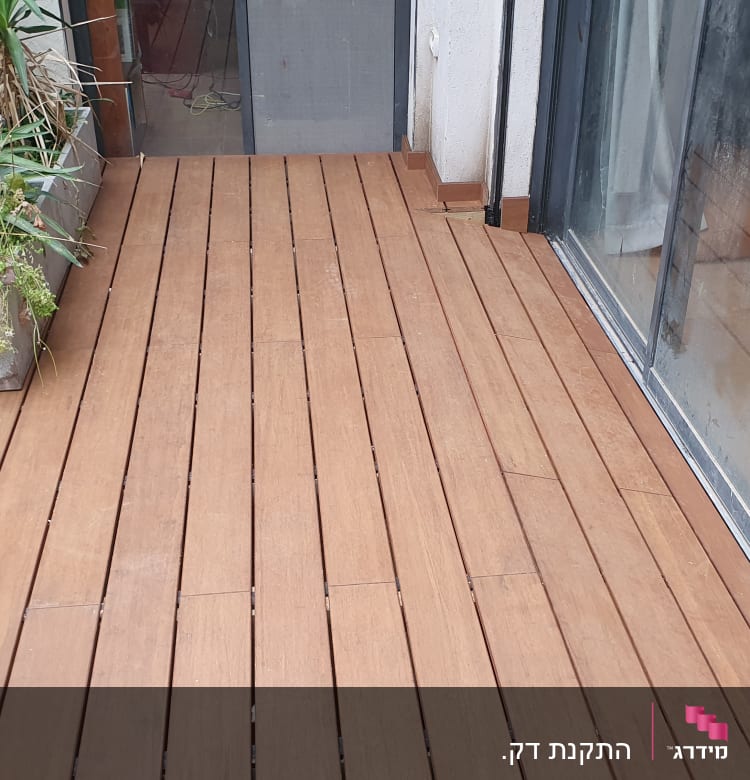 רצפת עץ במרפסת עם עציצים ירוקים